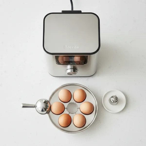Breville The One° Precision Poacher displayed with its accompanying egg tray, piercer, and egg topper.